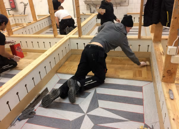 I de individuella övningsbåsen på Stockholms byggtekniska gymnasium tränar eleverna olika moment som ingår i golvläggaryrket.