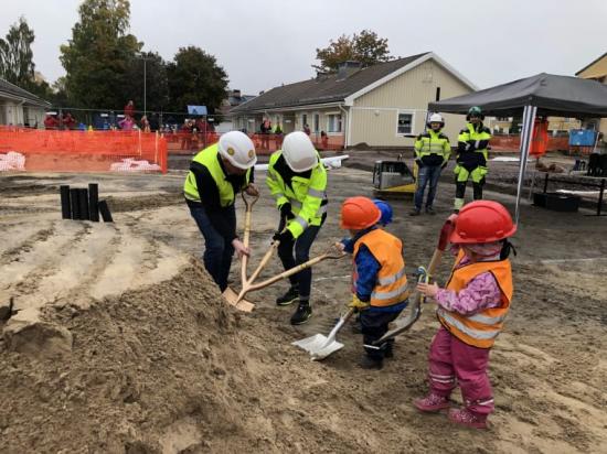 Ordförande i teknik- och fastighetsnämnden Henrik Lander (C) och projektledare Charlotte Stenberg får grävhjälp av några av barnen på Norrstrands förskola.