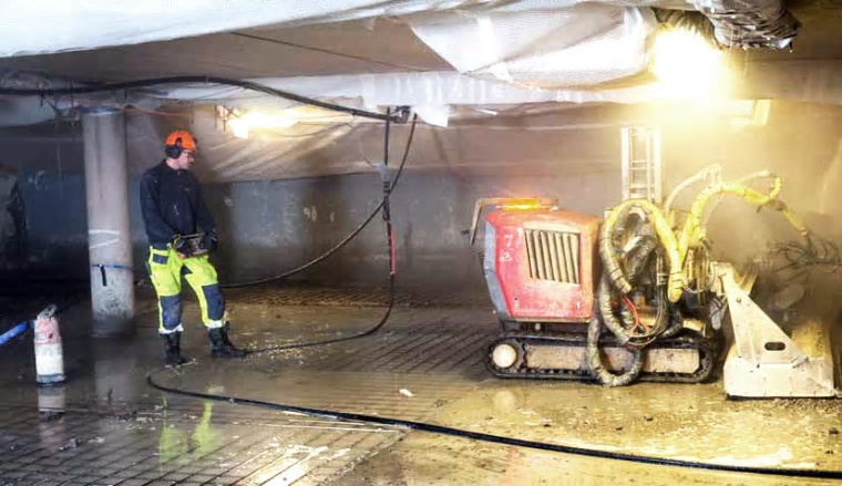 Vattenbilning med robotburen vattenbilningsutrustning i ett garage i Hammarby Sjöstad, Stockholm.